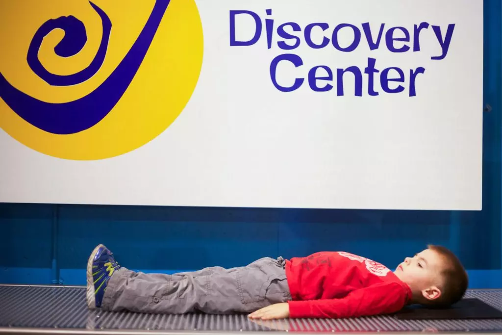 Child laying on Bed of Nails exhibit.