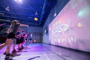 Children playing with a giant, projected, interactive screen on a wall using gym balls